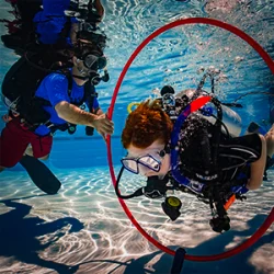 A child practices his scuba bouyancy by swimming through a hoop.