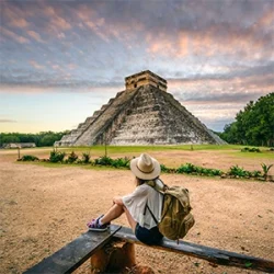A young woman, visiting Playa Mujeres, sits and watches Chichen Itza in the early morning