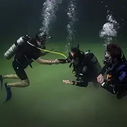 Two divers practice an scuba diving out-of-air exercise in Casa Cenote
