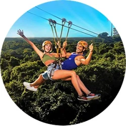 Couple smiling and waving while descending a zip-line at Xplor